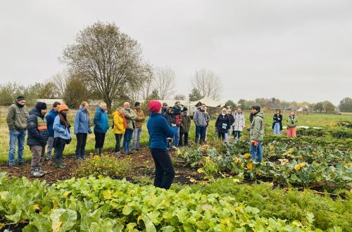 Een groep mensen krijgt uitleg op een agro-ecologische boerderij.