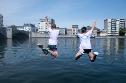 Twee mensen springen vrolijk in stedelijk water. 