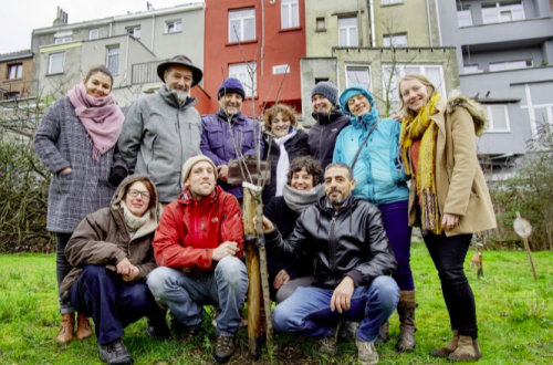 Een groep van 11 mensen die in een tuin staan bij een boom die ze zojuist plantte. Het begin van hun buurtboomgaard. 