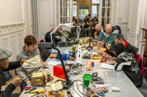 Een tafel waar mensen materialen repareren 