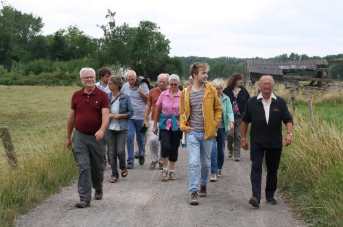 Een groep mensen wandelt langs groene velden. 