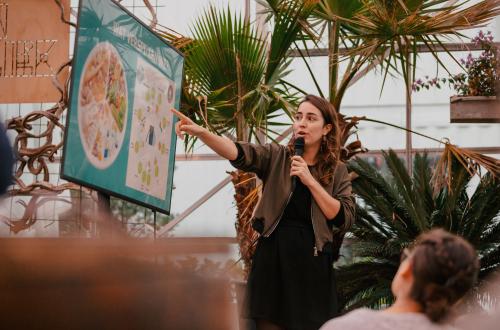 Een vrouw spreekt voor een publiek over voedselverspilling. 